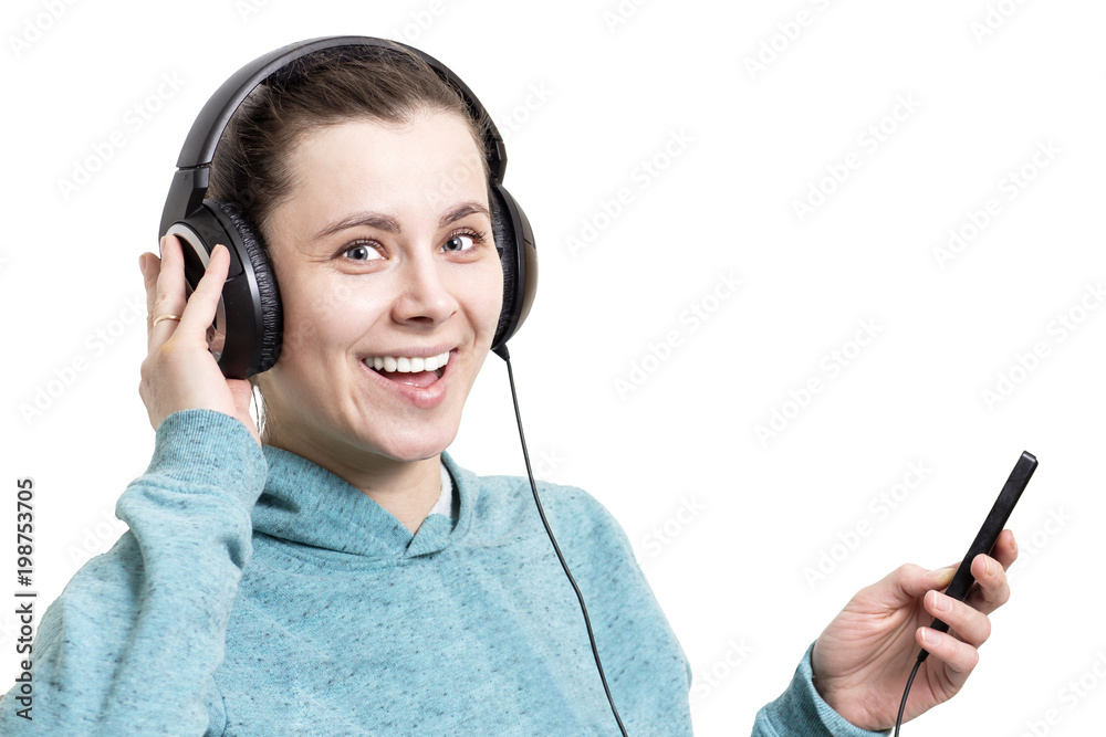 Happy young girl in headphones with player isolated on white background. A woman smiles and listens to music from the player. Music in headphones. Happy young girl in headphones with player isolated on white background. A woman smiles and listens to music from the player. Music in headphones.