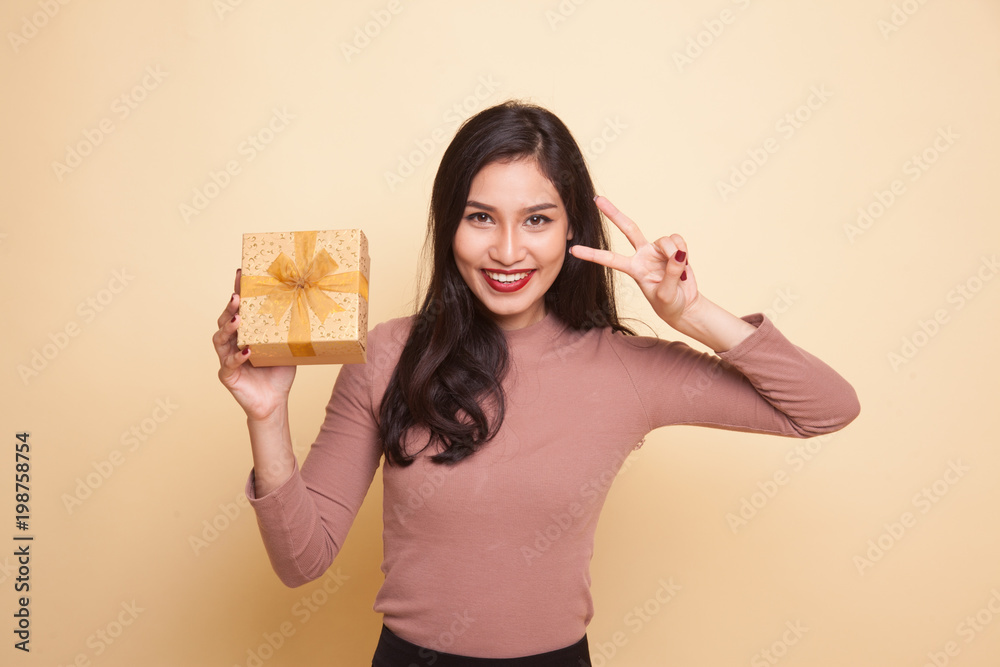 Young Asian woman show Victory sign with a gift box. Young Asian woman show Victory sign with a gift box.