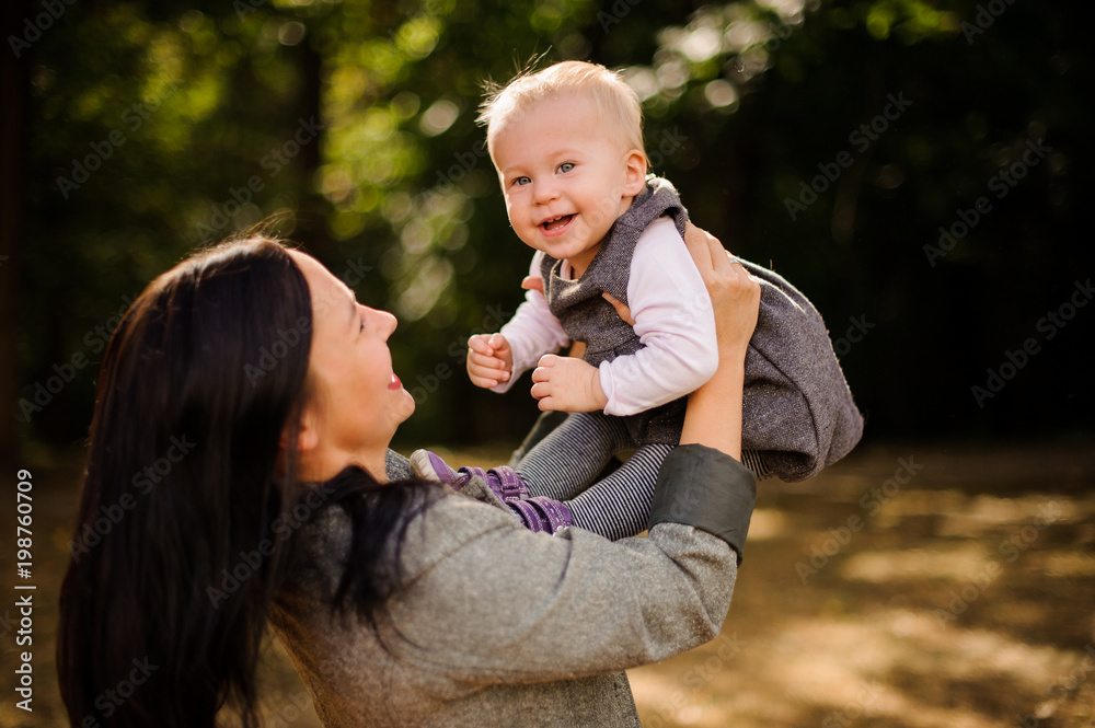 Happy brunette mother playing with a laughing baby daughter Happy brunette mother playing with a laughing baby daughter