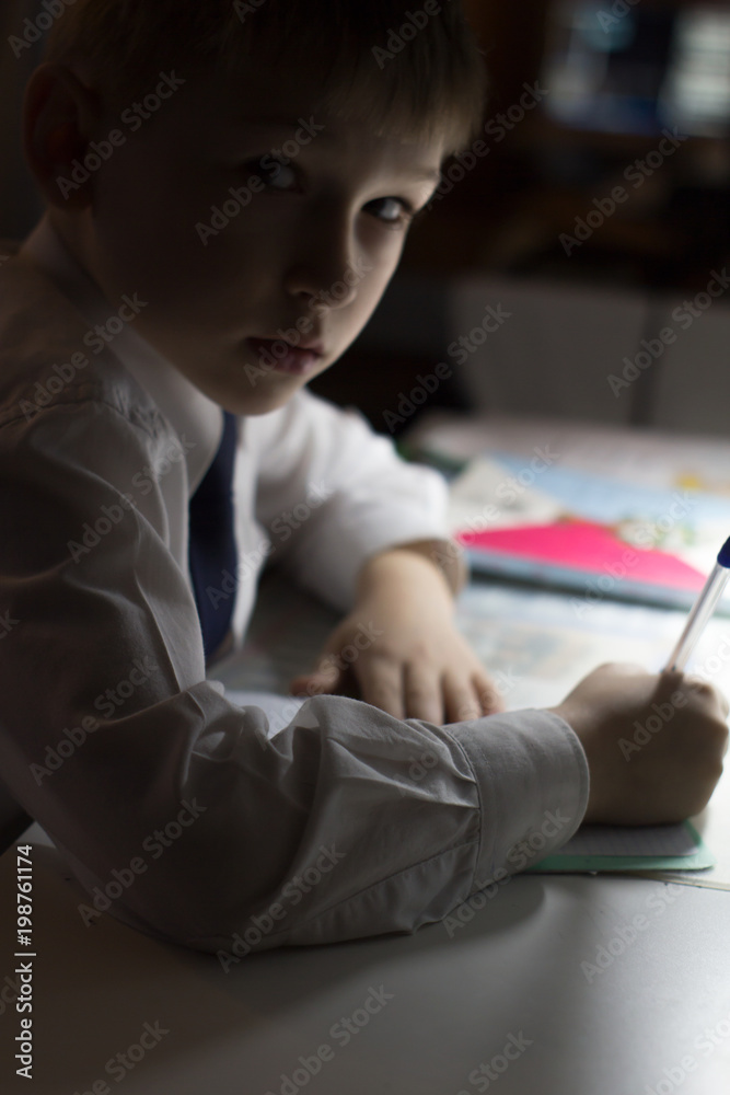Boy  with pencil writing english words by hand on traditional white notepad paper.