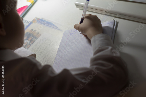 Boy  with pencil writing english words by hand on traditional white notepad paper. photo