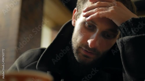 4k Bearded man frustratedly siting in cafe and thinking about ideas or own life close-up photo