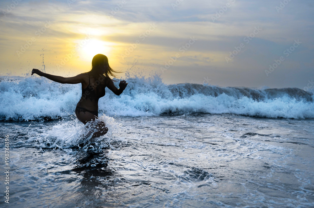 silhouette of young woman running happy on sea water playing with big waves free and joyful splashing on Summer sunset beach silhouette of young woman running happy on sea water playing with big waves free and joyful splashing on Summer sunset beach