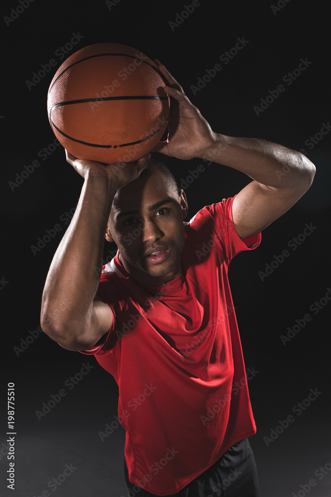 Fototapeta premium Top view portrait of young african sportsman wanting to cast basketball while raising it over the head. There is desire in his eyes to throw it in the purpose. Isolated
