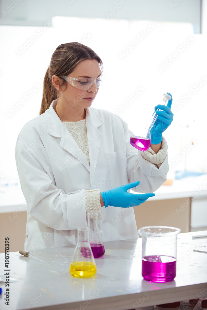 young woman scientist working with laboratory glassware with different colors liquid in a laboratory young woman scientist working with laboratory glassware with different colors liquid in a laboratory