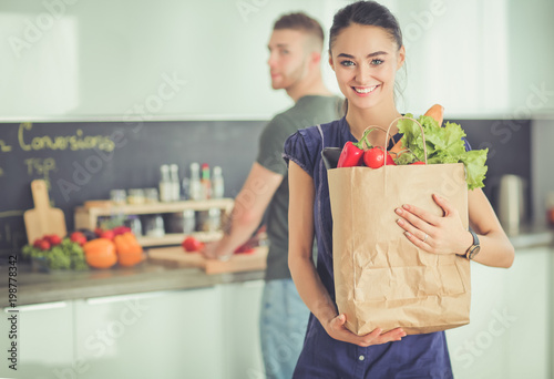 Young couple in the kitchen , woman with a bag of groceries shopping photo