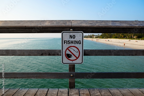 No Fishing Sign on Wooden Pier Against Sea and Beach