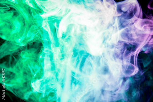 Colorful green and purple smoke on a black isolated background. Background from the smoke of vape