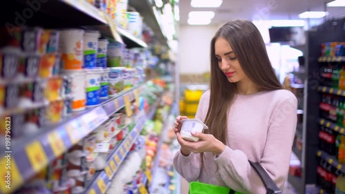 Woman chooses yogurt at a supermarket. 4 k photo