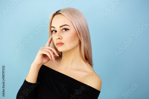 Beautiful girl on blue background. The girl looks at you and thinks. Place for text