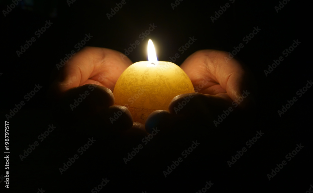 Cupped hands with burning candle