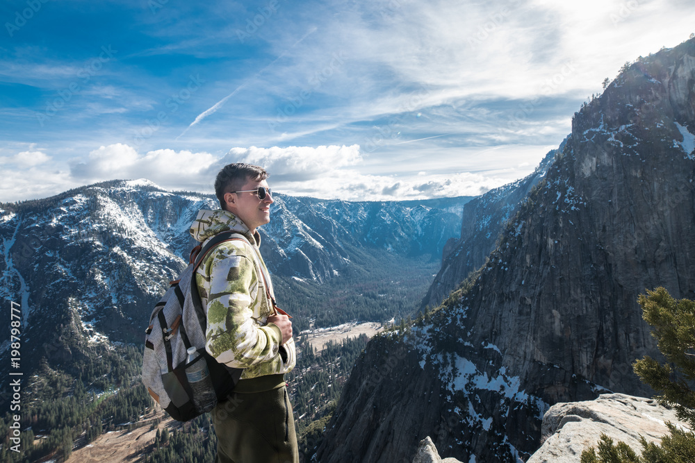 Tourist man with backpack enoy the view on mountain top in Yosemite National Park