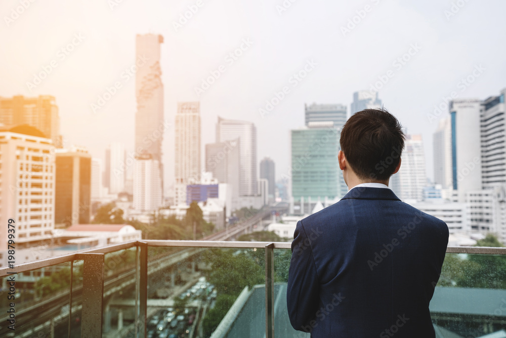 Businessman in blue suit looking at city view in Bangkok city, Thailand Businessman in blue suit looking at city view in Bangkok city, Thailand