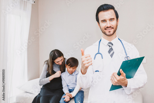 Doctor with cute little boy and mom showing thump up OK signs in hospital