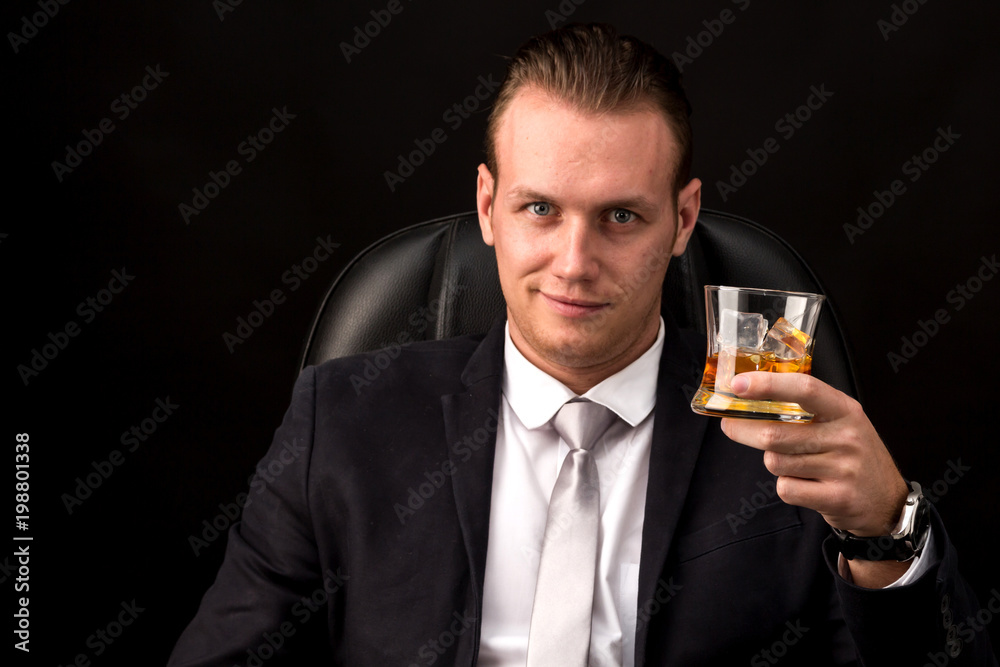 Portrait of Businessman in black suit drinking a whiskey on black background Portrait of Businessman in black suit drinking a whiskey on black background