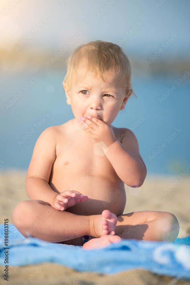 Baby playing with toys on the sandy beach near the sea. Cute little kid in  sand on tropical beach. Ocean coast.