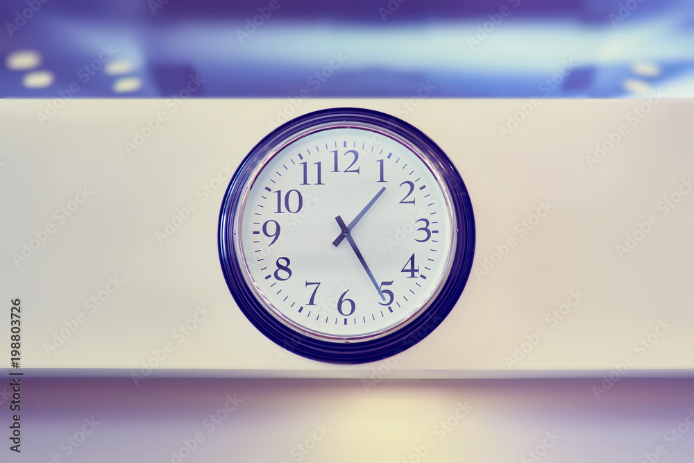 Classic round wall clock, round watch with black arrows hanging on the wall.on office wall background. Classic round wall clock, round watch with black arrows hanging on the wall.on office wall background.