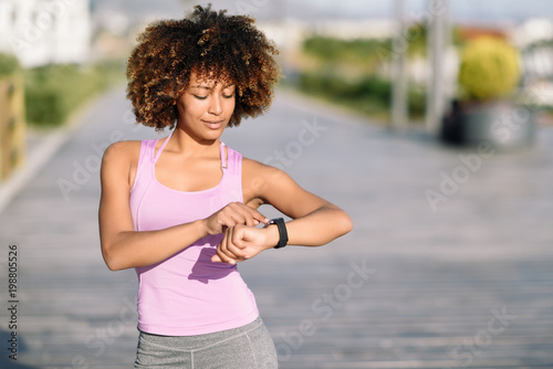 Young black woman using smartwatch touching touchscreen