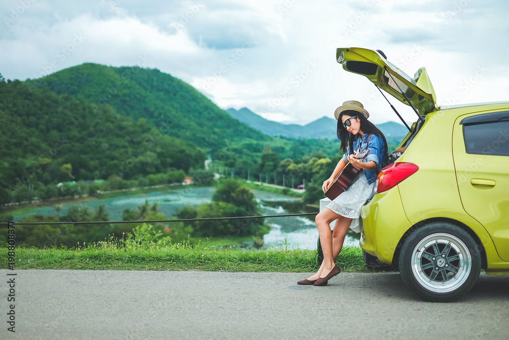 Woman tourist sitting on hatchback car and playing guitar background is   traveler young girl enjoying on holiday. Stock Photo | Adobe  Stock
