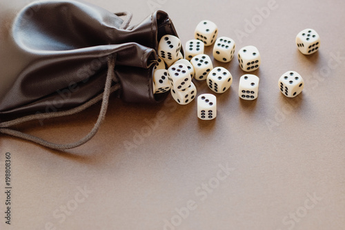 Set of gaming dice rolled out of leather bag on brown background. Concept with copy space for games, game board, role playing game, chance, good luck or gambling. Toned image top view. Close-up. photo