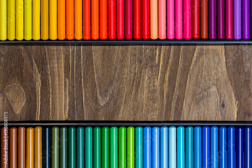 Image of the multicolored pencils, two horizontal rows, wooden background