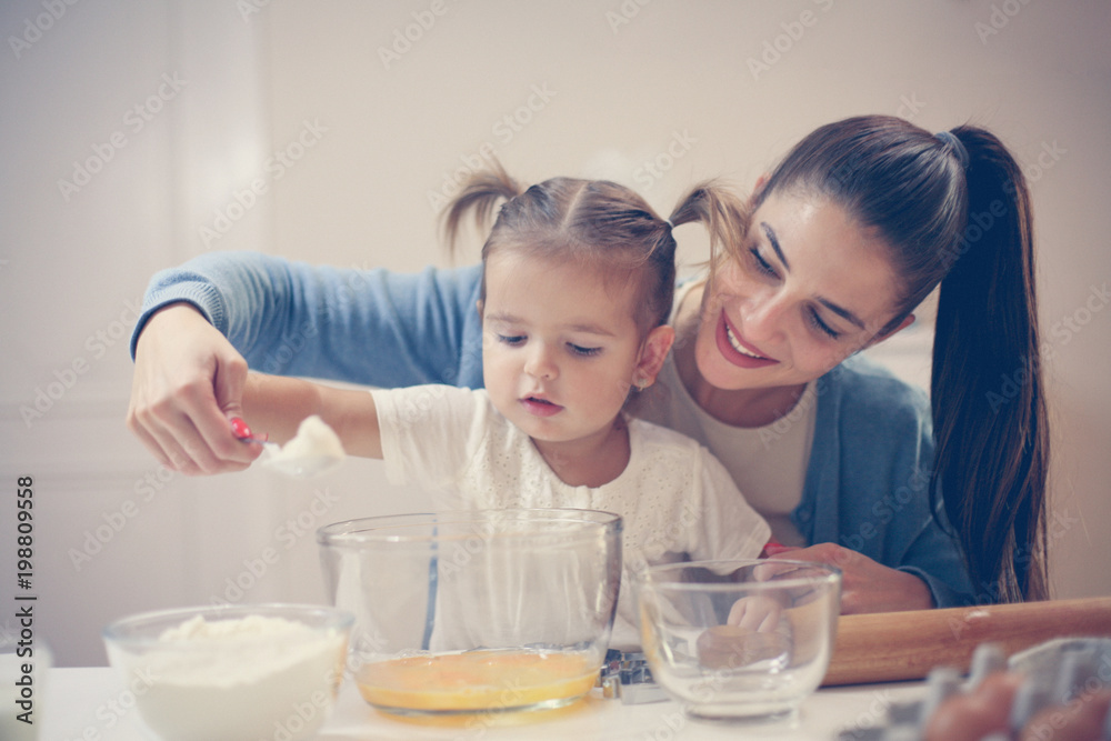 Single mother and smiling girl baking cookies together. Single mother and smiling girl baking cookies together.