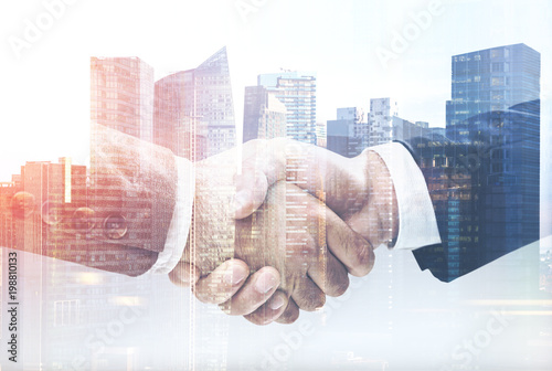 Two businessmen shake hands in a city close up