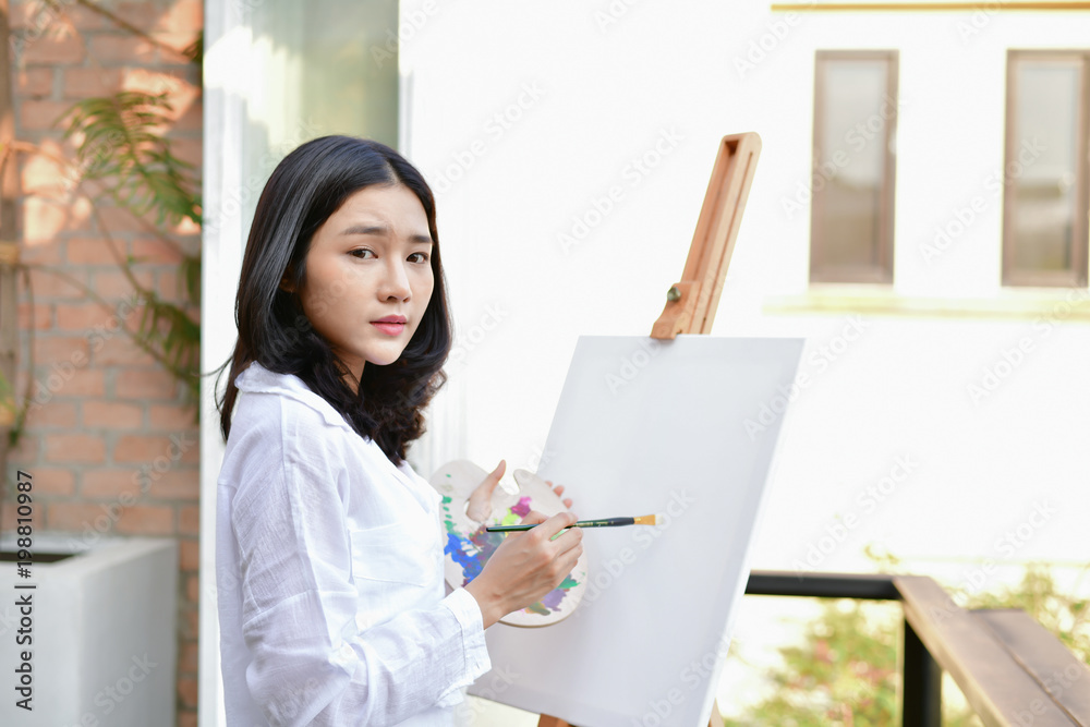 Concept Artist Beautiful girl. Beautiful women are creating art. Beautiful woman is painting happily. Young artist painting outside the house. Concept Artist Beautiful girl. Beautiful women are creating art. Beautiful woman is painting happily. Young artist painting outside the house.