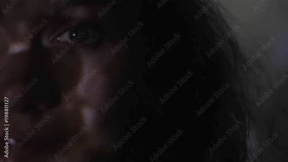 Close up portrait of a young woman watching a video or film on TV or a computer monitor. Reflection on her face Close up portrait of a young woman watching a video or film on TV or a computer monitor. Reflection on her face
