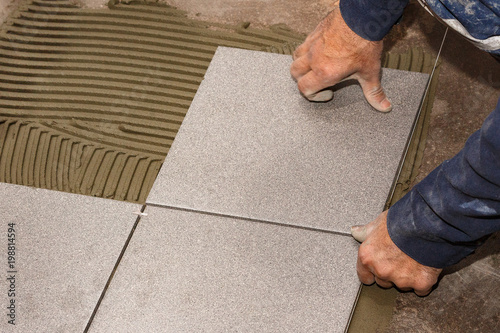 Hands of the worker lay ceramic granite on the floor. Close-up.