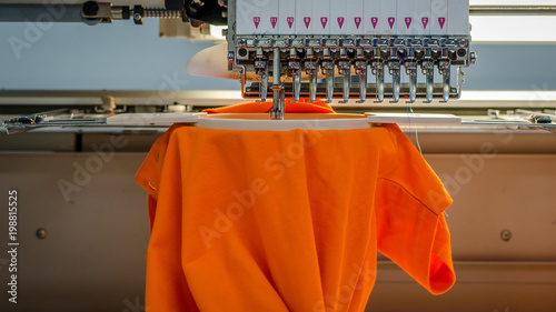 Embroidery machine from the front, stiching a orange poloshirt