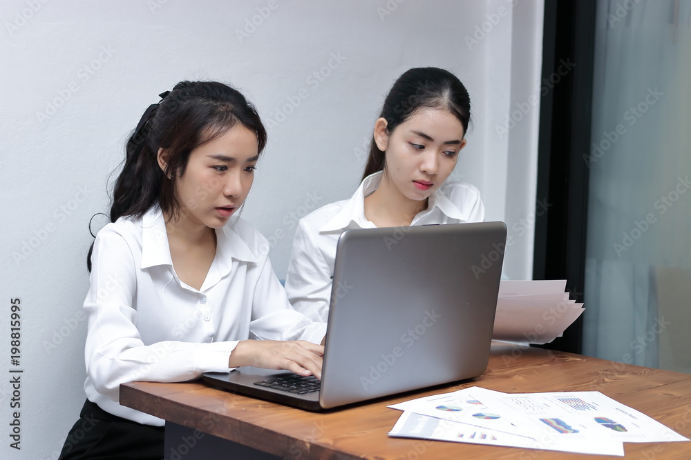 Two attractive young Asian businesswoman using laptop together in modern office. Team work business concept.