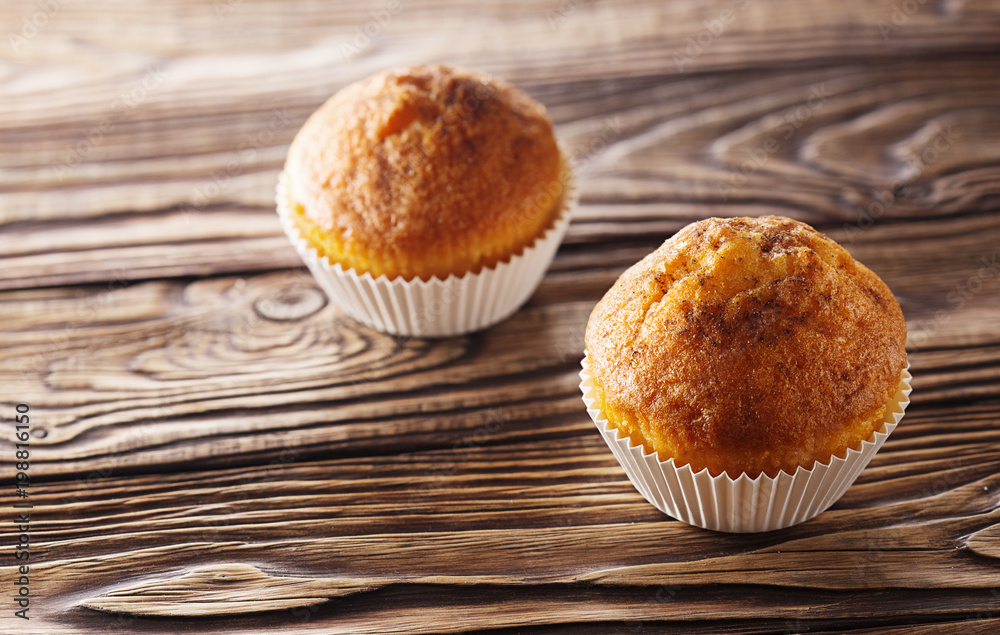 Classic muffins on a wooden old background in a white wrapper. Classic muffins on a wooden old background in a white wrapper.