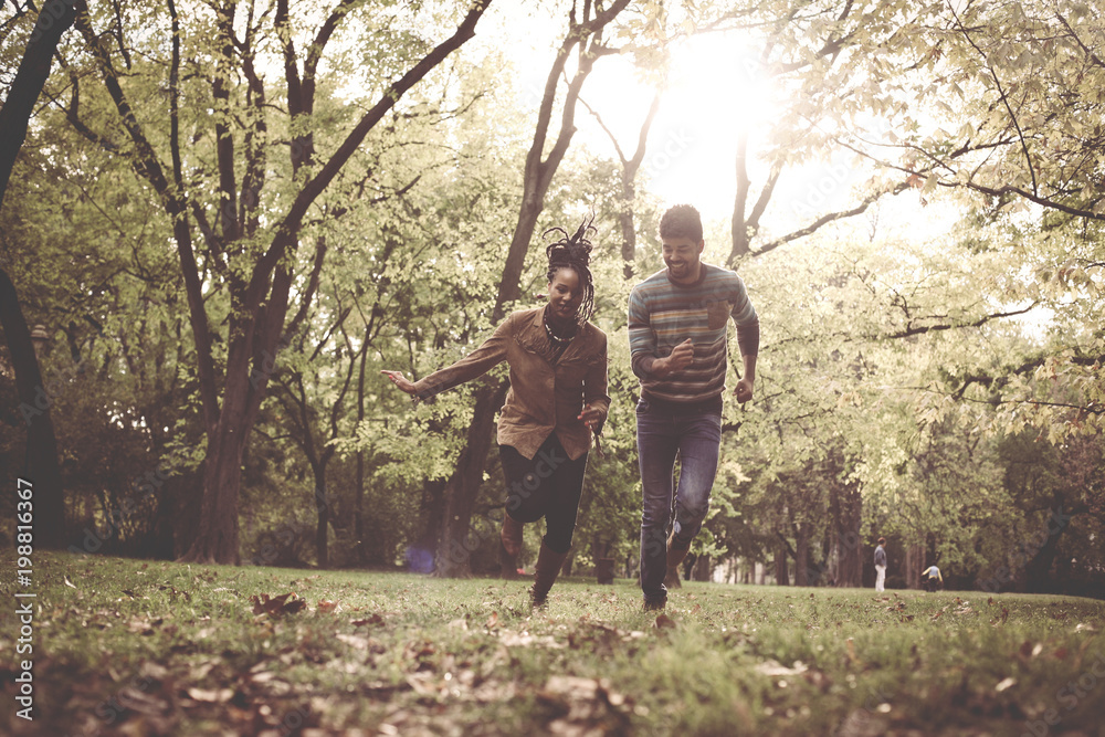 Happy African American couple running and catching in park.