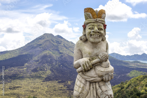 Traditional Balinese sculpture against the background of the volcano Batur. Island Bali, Indonesia