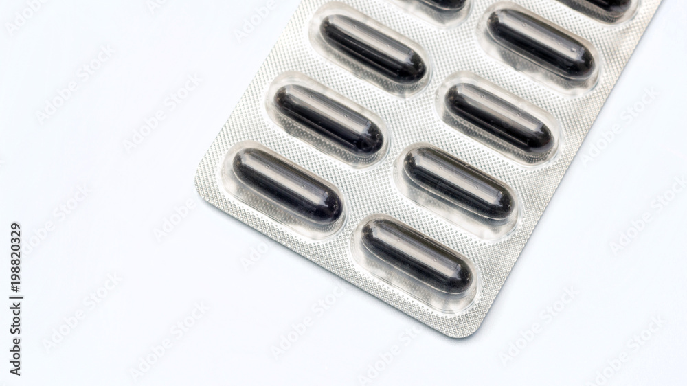 Black pill capsule on a white background., selective focus. Black pill capsule on a white background., selective focus.
