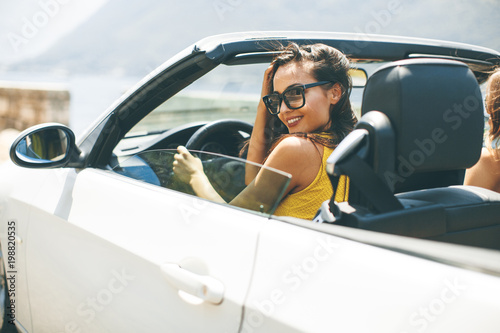 Pretty young woman in white cabriolet car