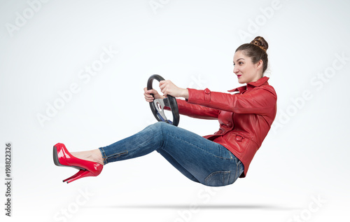 Young woman in red leather jacket with car steering wheel, auto concept