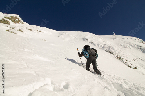 hiker with snowshoes go higher to the top of mount in the fresh snow