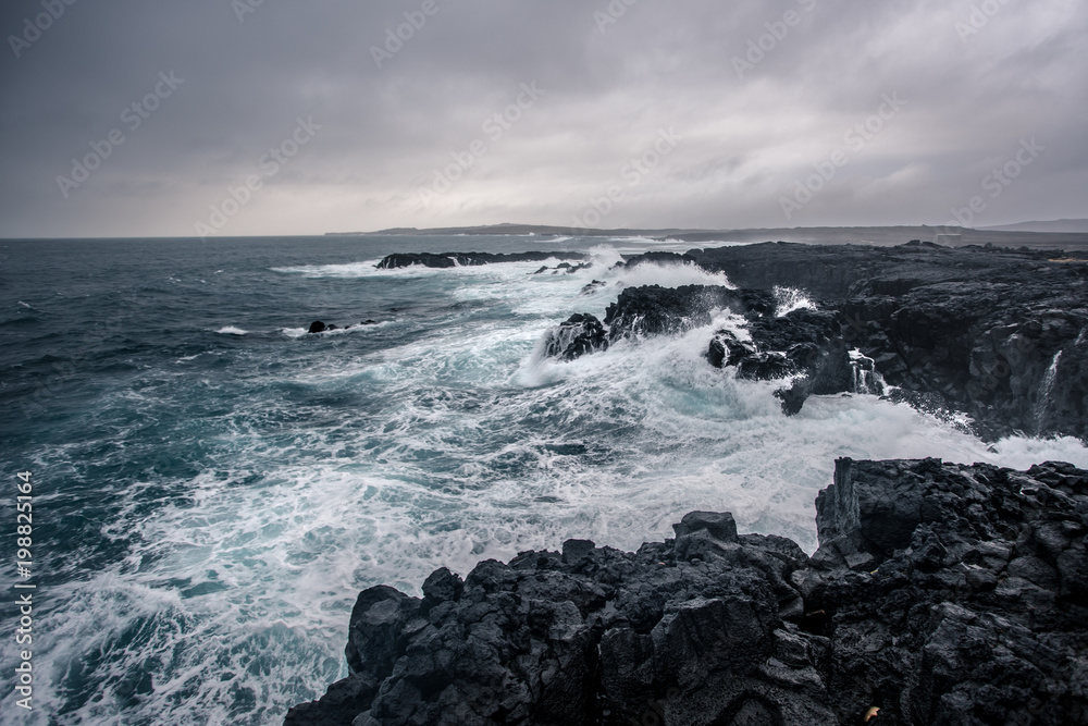 Rugged Icelandic coastline with big  waves hitting the black rocks at overcast evening in south west Iceland.