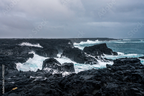 Rugged Icelandic coastline with big waves hitting the black rocks at overcast evening in south west Iceland.