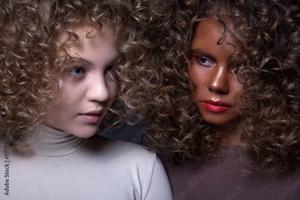 Portrait of two beautiful teenage girls with afro hair curls and creative make-up.
