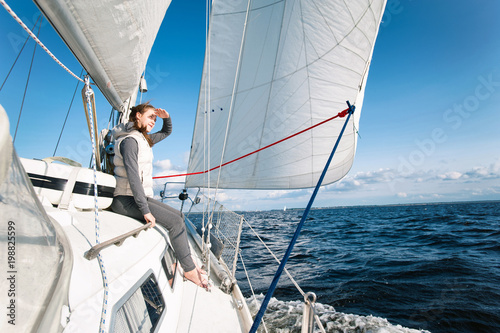 Young girl looking forward sitting on yacht desk having trip