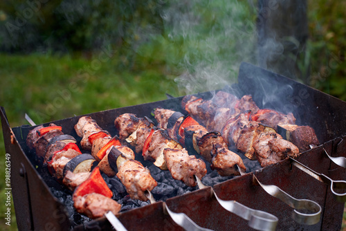 Meat roasting on skewers, summer picnic concept. Meat on skewers cooked on grill. Charcoal grill cooking