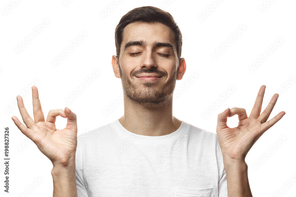 Concentrated relaxed man standing with closed eyes, having relaxation while meditating, trying to find balance and harmony. Yoga and meditation concept Concentrated relaxed man standing with closed eyes, having relaxation while meditating, trying to find balance and harmony. Yoga and meditation concept
