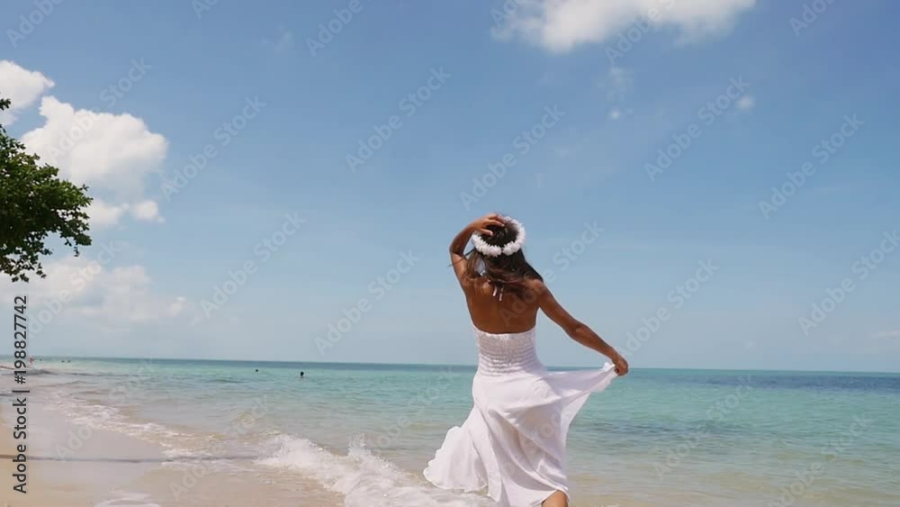 Attractive young joyful woman in a white dress and flower wreath runs along the seacoast barefoot and enjoys herself. Beach with white sand. Slow Motion. 1920x1080 Attractive young joyful woman in a white dress and flower wreath runs along the seacoast barefoot and enjoys herself. Beach with white sand. Slow Motion. 1920x1080