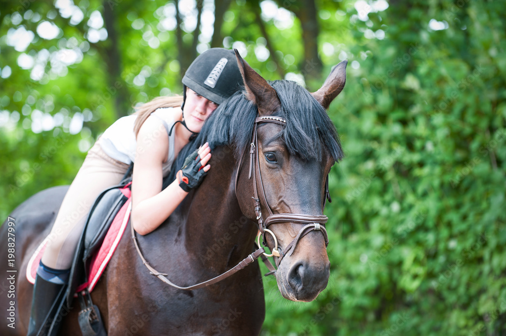 Young teenage lady-equestrian embracing her favorite frend-brown horse.