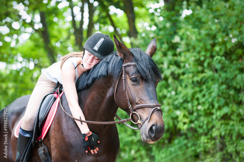 Young teenage girl-equestrian embracing her favorite frend-brown horse.