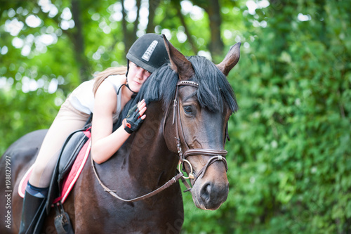 Young teenage lady-equestrian embracing her favorite frend-brown horse.