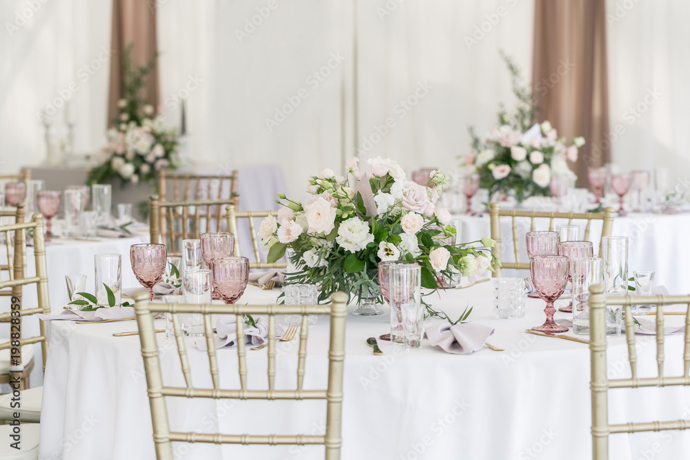 Beautiful table setting with crockery and flowers for a party, wedding reception or other festive event. Glassware and cutlery for catered event dinner.